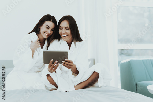 Girls In A Bathrobes Are Looking At Tablet Screen.