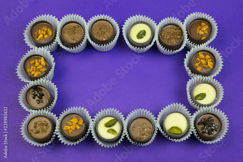 Frame of chocolates. Place for text inside the candy with different fillings on a colored background.