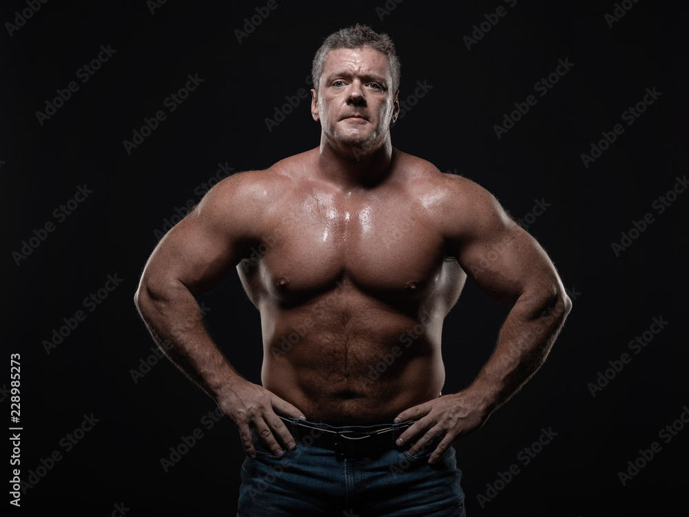 Powerful muscular bodybuilder posing on a black background. concept of strength and health Powerful muscular bodybuilder posing on a black background. concept of strength and health
