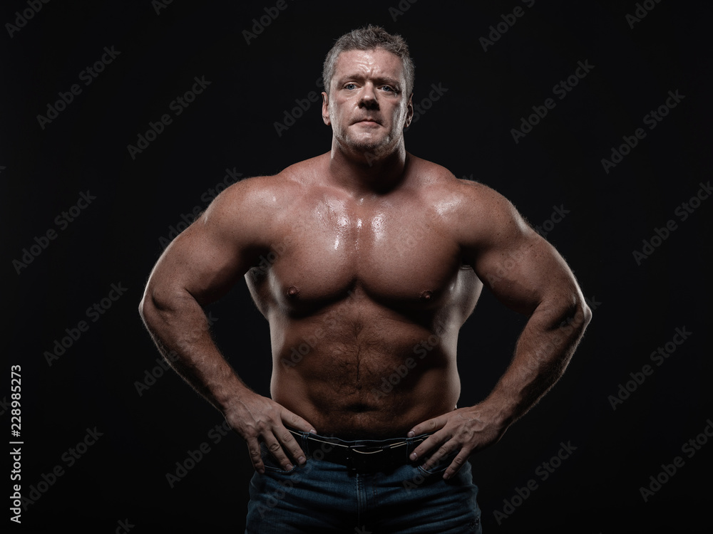 Powerful muscular bodybuilder posing on a black background. concept of strength and health