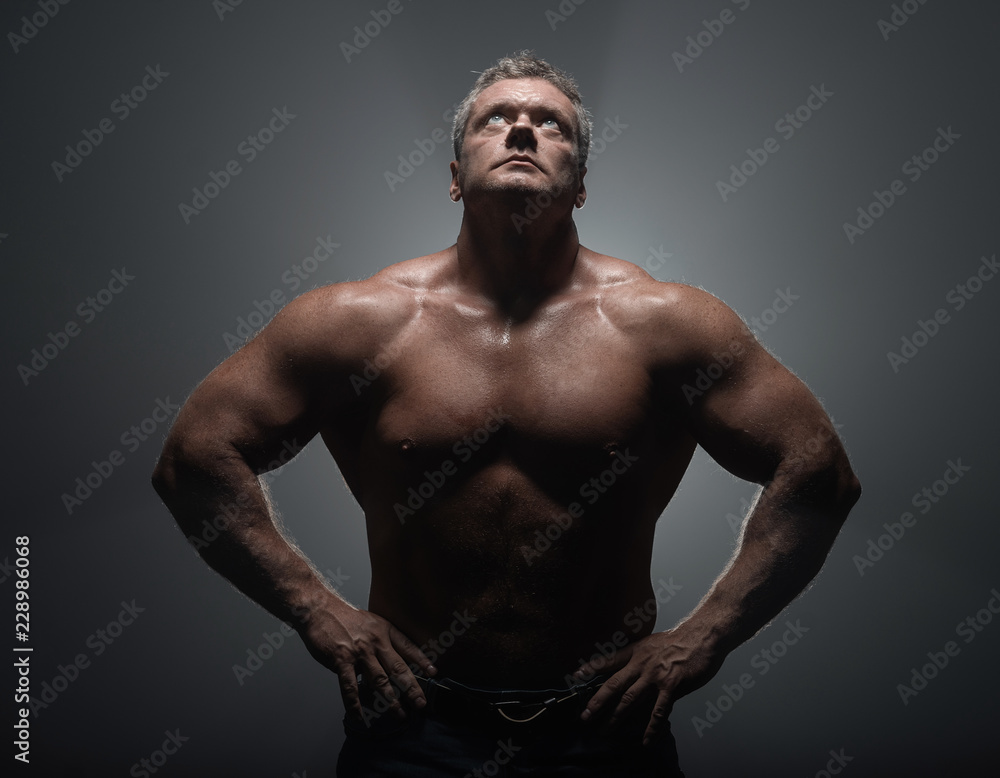 Powerful muscular bodybuilder posing on a black background. concept of strength and health Powerful muscular bodybuilder posing on a black background. concept of strength and health