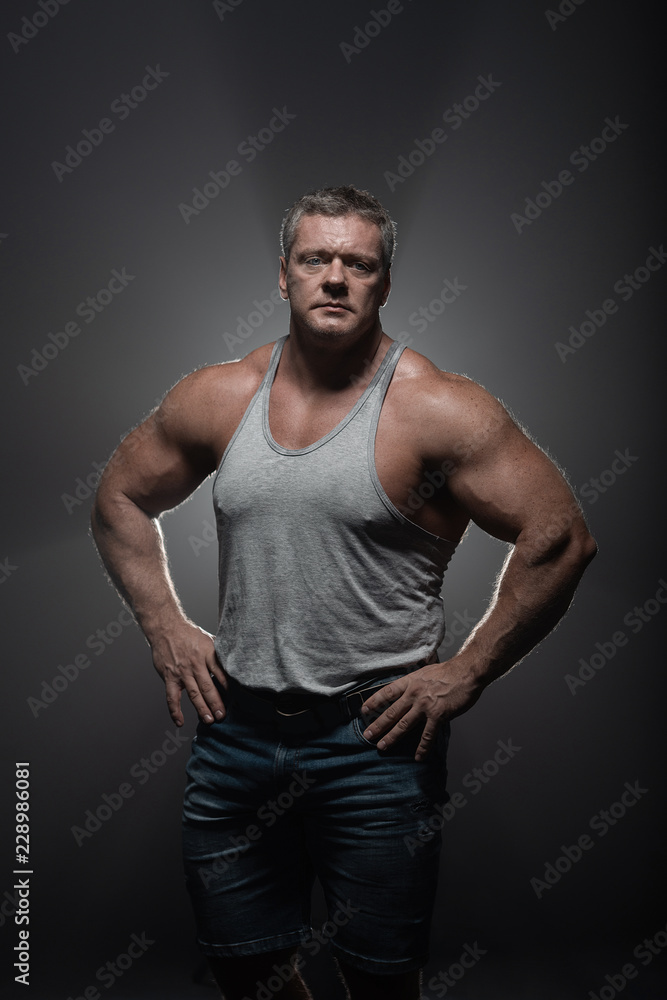 Naklejka premium Powerful muscular bodybuilder posing on a black background. concept of strength and health