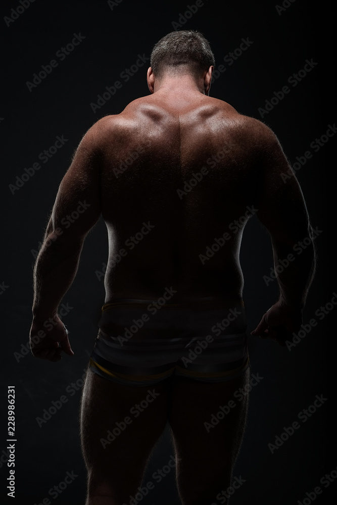 Muscular man with a powerful back posing on a black background. concept of sports and fitness