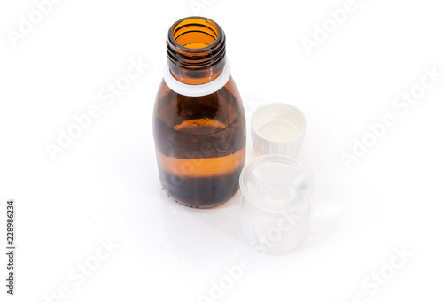 Brown bottle with medical mixture and medicine measuring cup