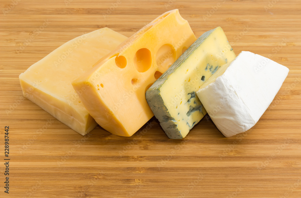 Pieces of various cheese on the bamboo cutting board