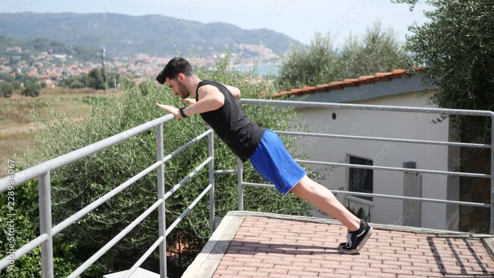 Athletic attractive young man exercising and stretching outdoor on terrace in summer day Athletic attractive young man exercising and stretching outdoor on terrace in summer day