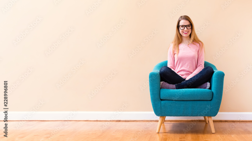 Happy young woman in a big chair smiling in a big open room Happy young woman in a big chair smiling in a big open room