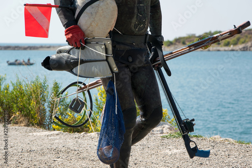 Crop view of scuba diver adult man on a seashore with spearfishing gear (fins, speargun)