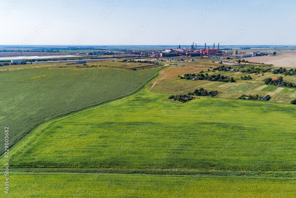 European plain landscape, view from a great height. In the distance are visible factories European plain landscape, view from a great height. In the distance are visible factories