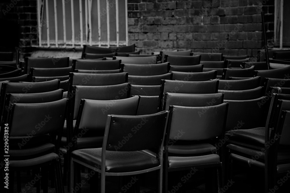 Fototapeta premium Chairs Stacked In A Dark Alleyway For Storage