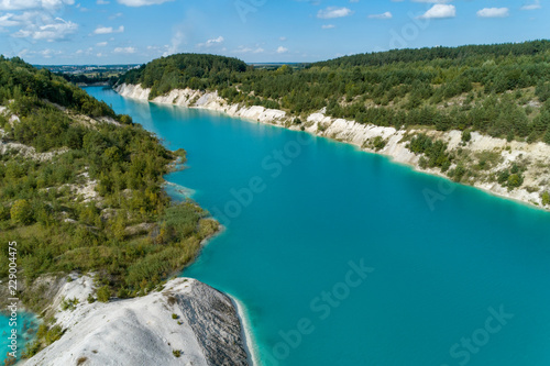 Abandoned mountain quarry. The mine workings are filled with water of a deep blue color. Aerial view