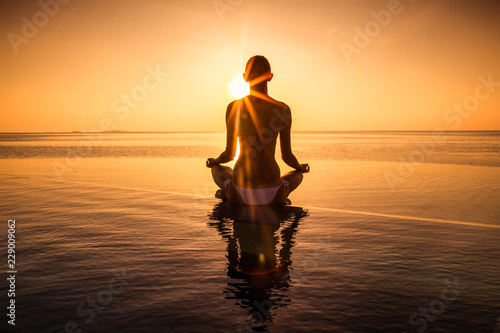 Woman has meditation and Yoga at infinity pool during sunset. © Aleksandar Todorovic