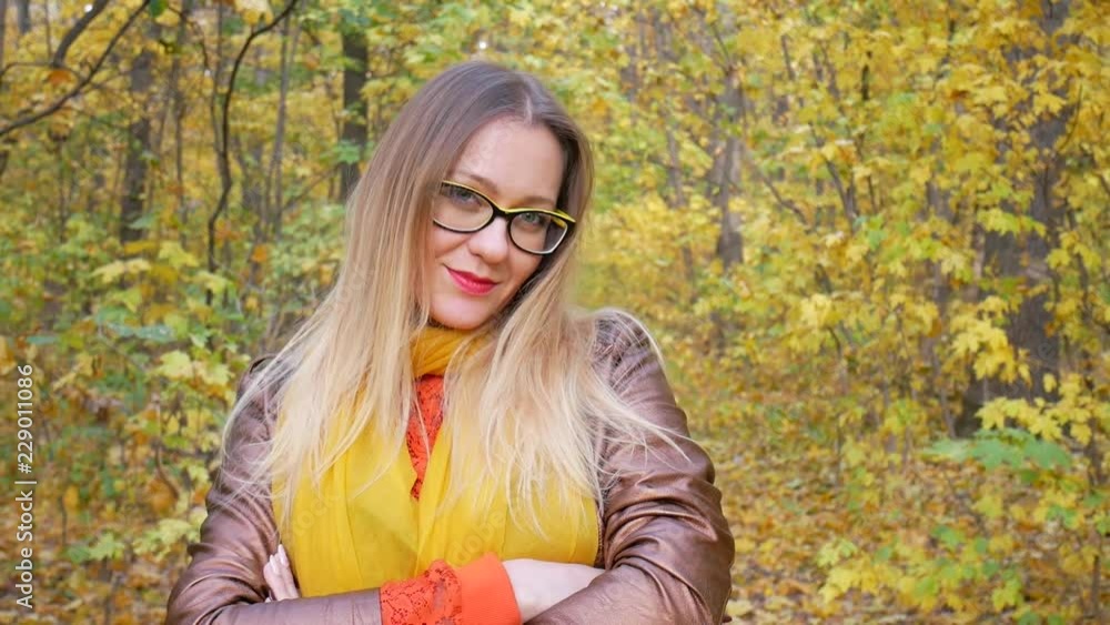 Portrait of beautiful woman wearing yellow glasses at park in autumn with colorful leaves and trees background Portrait of beautiful woman wearing yellow glasses at park in autumn with colorful leaves and trees background