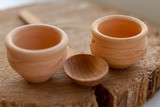 Ethnic authentic pottery: two small bowls and a wooden spoon on a cut of wood. Close-up. Selective focus. Concept for festivals of national handicraft.
