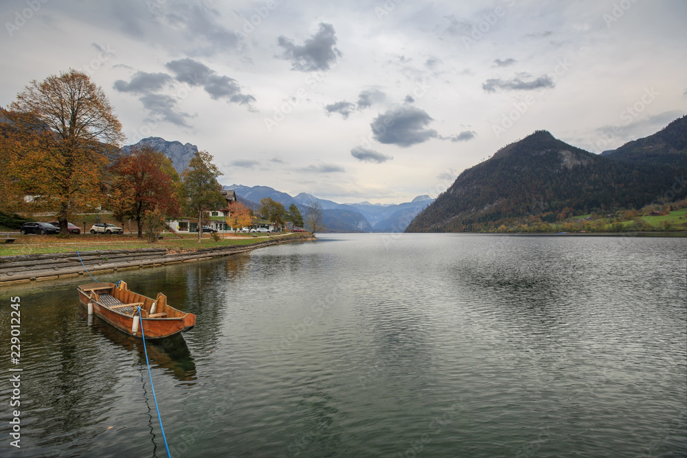 A moored wooden boat at the Grundlsee lake. View of the Alps. Salzkammergut, Styria, Austria. A moored wooden boat at the Grundlsee lake. View of the Alps. Salzkammergut, Styria, Austria.