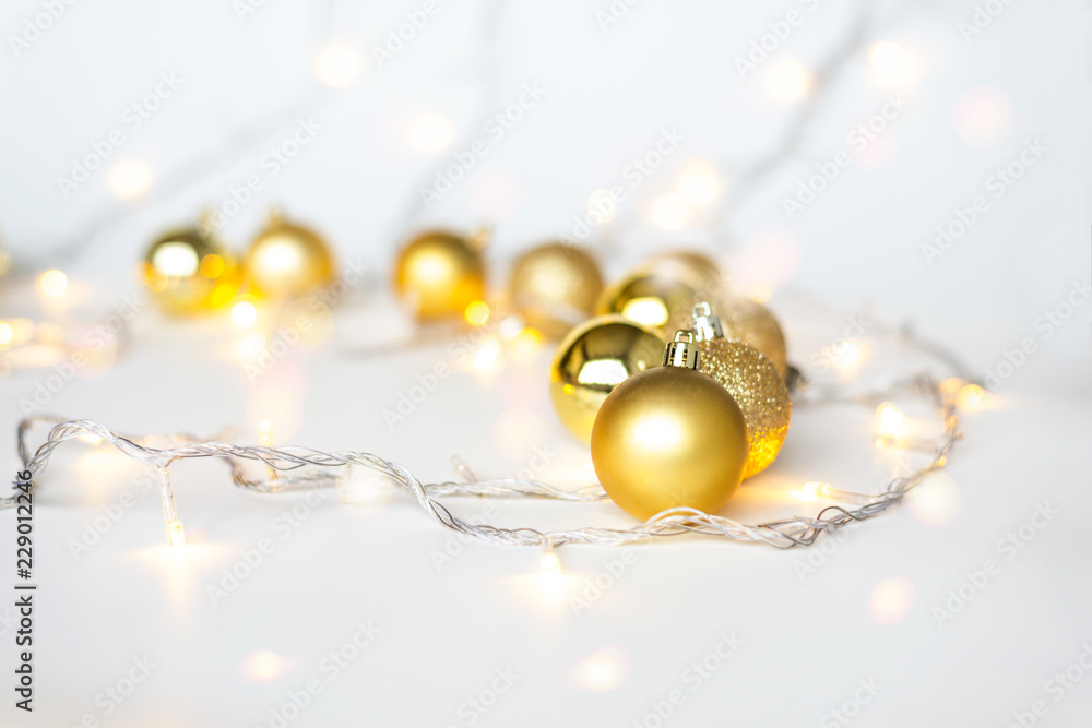 Christmas lights in warm yellow white on string and gold xmas balls over light background with copy space for text, logo decoration on Xmas eve celebration, special holidays, new year event concept Christmas lights in warm yellow white on string and gold xmas balls over light background with copy space for text, logo decoration on Xmas eve celebration, special holidays, new year event concept