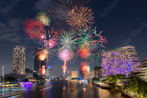 Photography New Year Fireworks at midnight over clear sky above river city surrounding with
