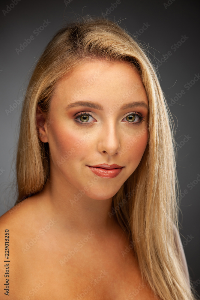 Makeup or skincare conceptual - beauty portrait of a young blonde woman with green eyes over dark gray background Makeup or skincare conceptual - beauty portrait of a young blonde woman with green eyes over dark gray background