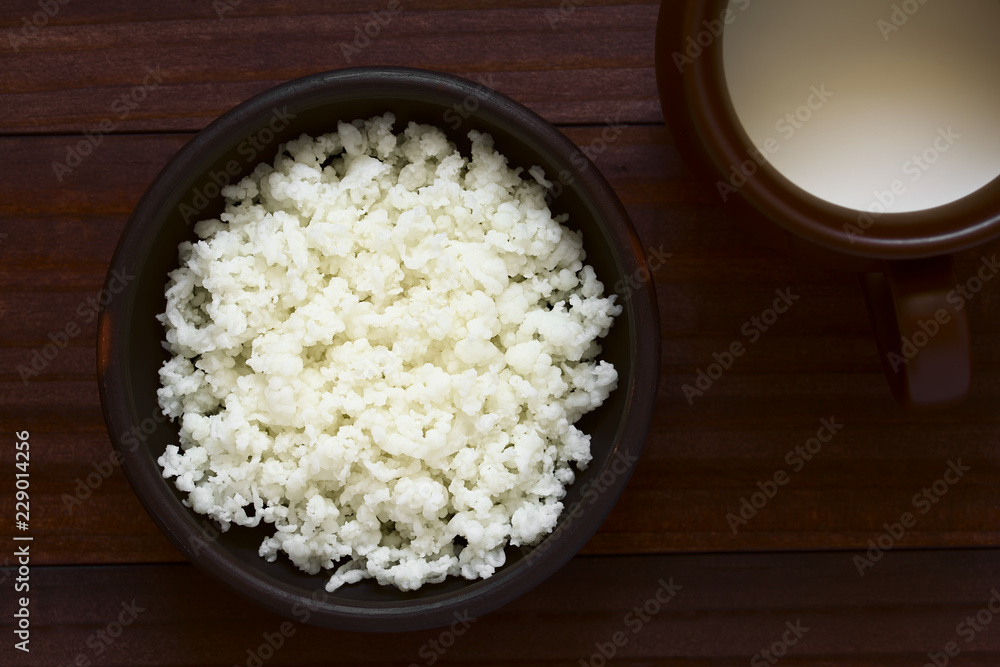 Kefir grains in bowl and a cup of milk on the side, photographed overhead with natural light (Selective Focus, Focus on the kefir grains) Kefir grains in bowl and a cup of milk on the side, photographed overhead with natural light (Selective Focus, Focus on the kefir grains)