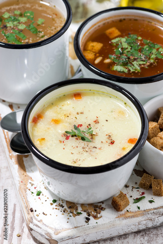 assortment of hot soups in mugs, vertical top view