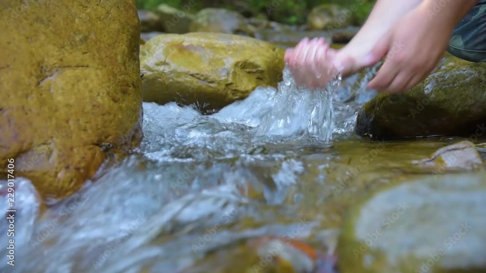 Hiker washing hands in stream Hiker washing hands in stream