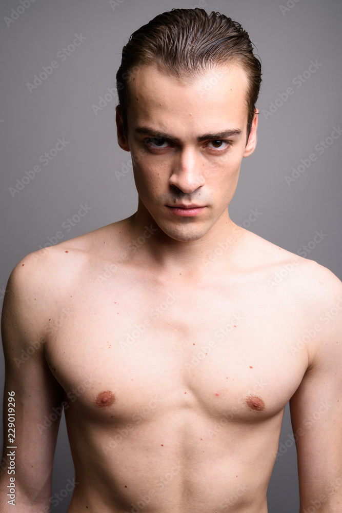 Young handsome man shirtless against gray background Young handsome man shirtless against gray background