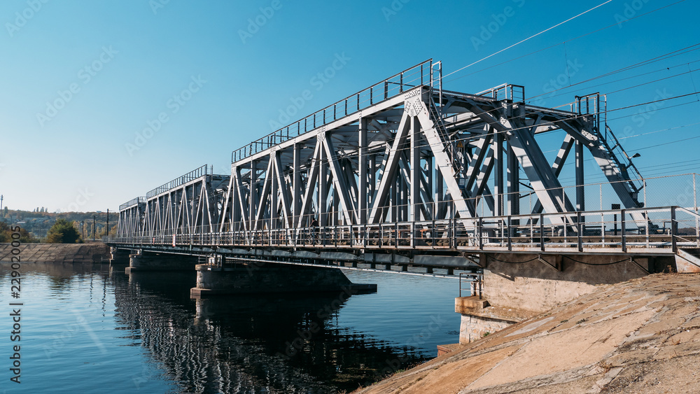 Steel railway bridge over river, perspective. Train transportation