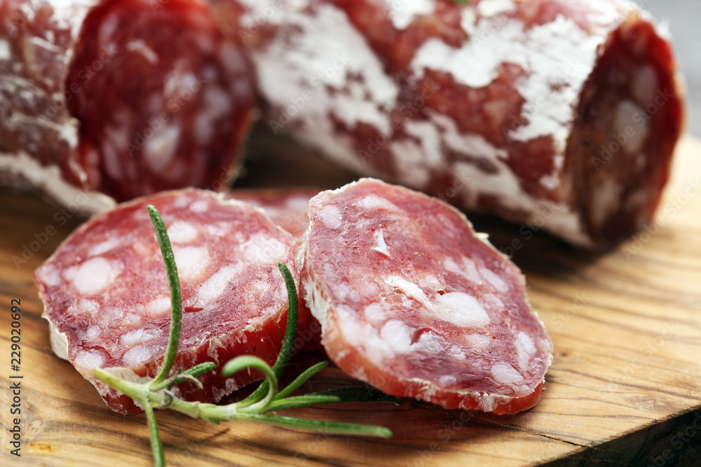 thinly sliced salami on a wooden texture on the background. thinly sliced salami on a wooden texture on the background.