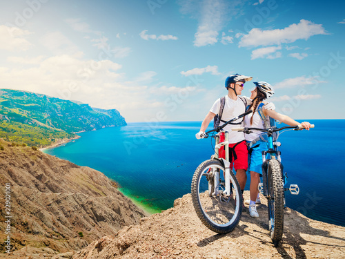 Happy couple of cyclists on mountain bikes embracing the beautiful landscape. Traveling by bicycle, man and woman. Sports lifestyle.