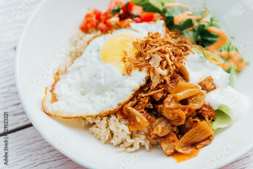 Fusion food Rice bowl toppings kimchi pork, organic fried egg, Korean eggplant and salad.