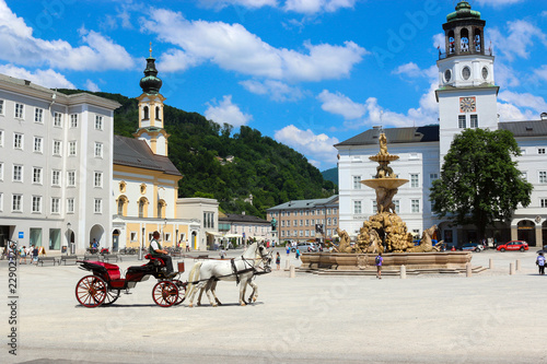 Salzburg, Austria - June 27, 2016: Panoramic view of Salzburg square, Austria, Europe. Summer day with blue clouds on sky. People walk in center park