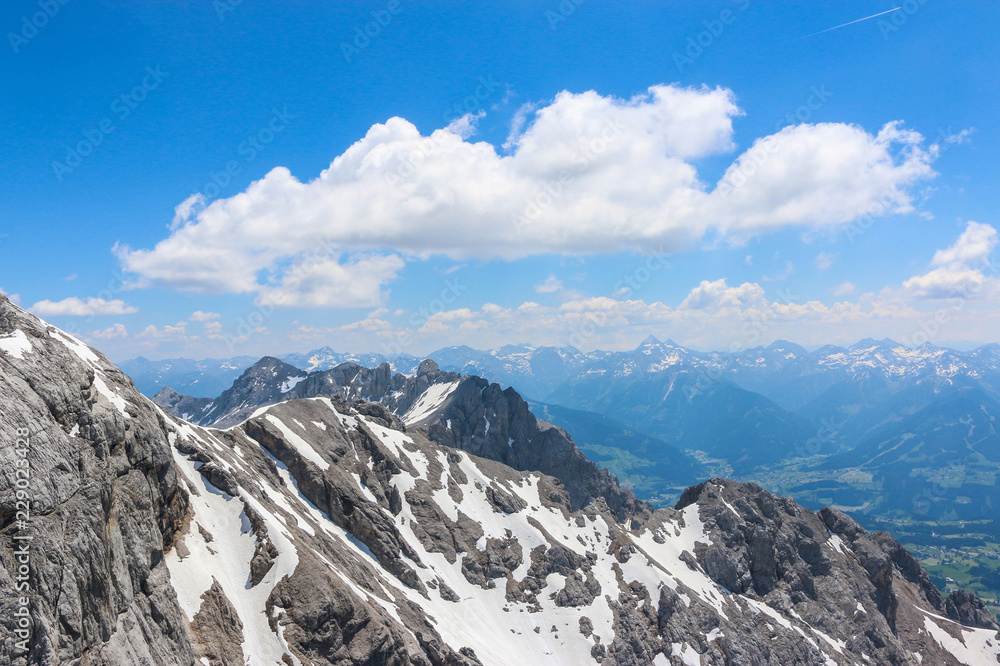 On peak of Dachstein and view alpine mountains. National park in Austria, Europe. Blue and cloudy sky in summer day