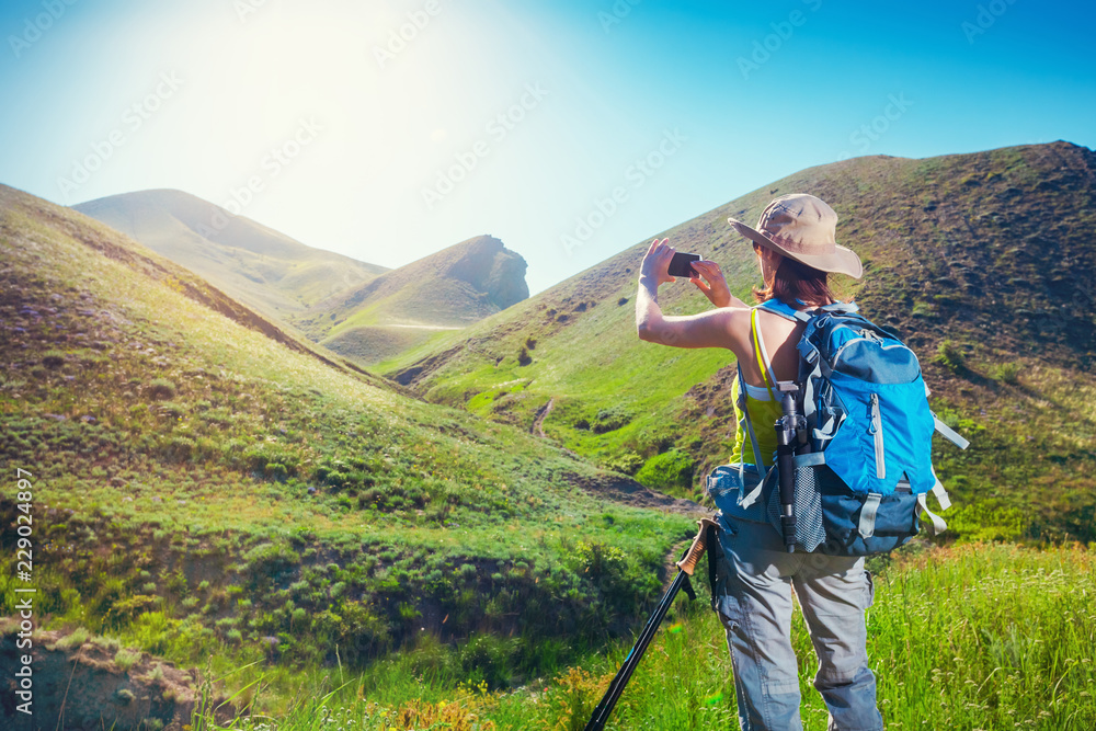 Woman hiker taking photo with smartphone at mountain nature. Backpacker photographs on a mobile phone.