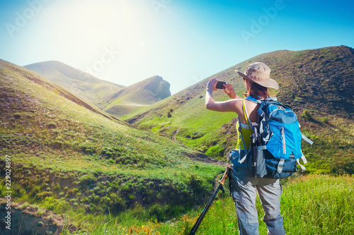 Woman hiker taking photo with smartphone at mountain nature. Backpacker photographs on a mobile phone.