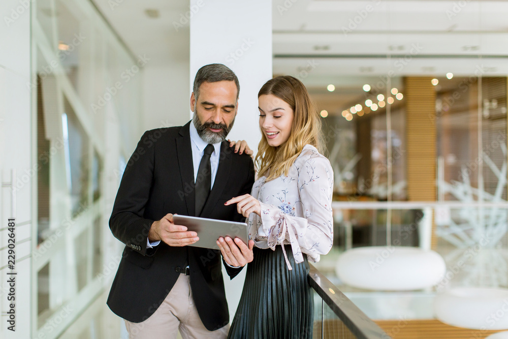 Young businesswoman and businessman look on digital tablet and discuss aout project Young businesswoman and businessman look on digital tablet and discuss aout project