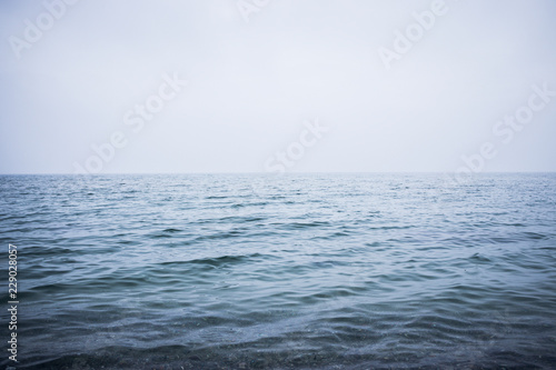 Clean and calm blue sea or ocean. Mist above the water surface. Image with place for your text.