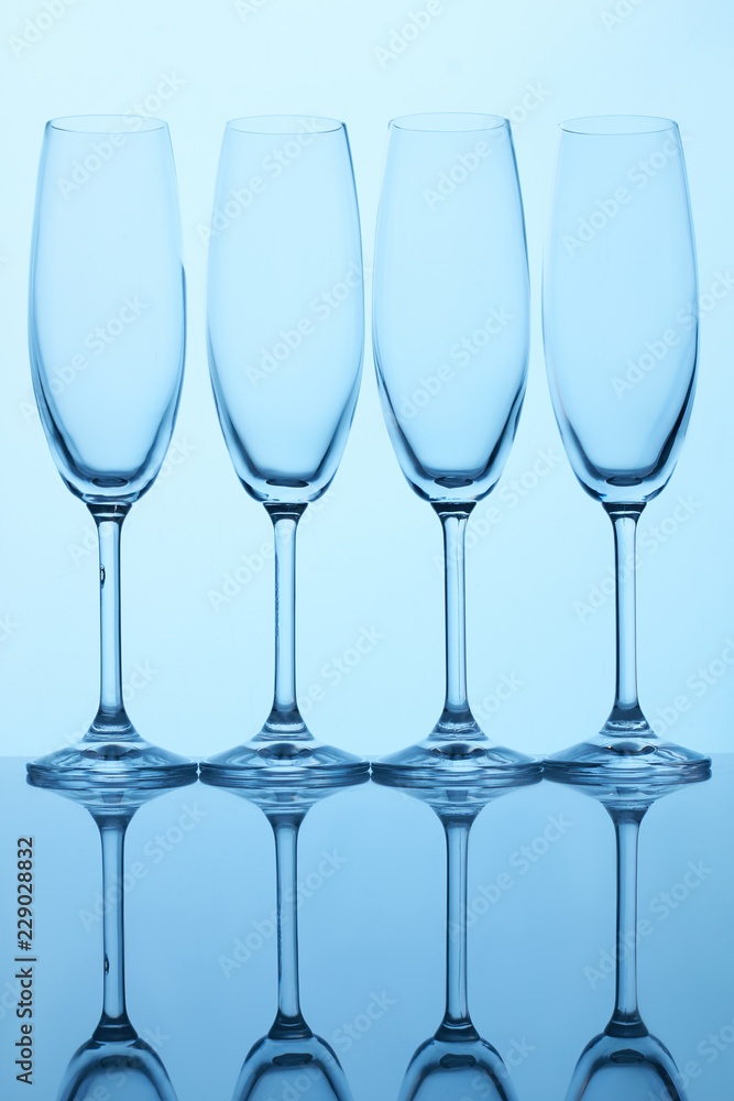 Four champagne glass cups. Reflective surface, blue lighting. Four champagne glass cups. Reflective surface, blue lighting.