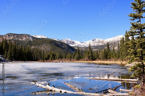 Colorado Forest and Snowcapped Mountain Background with Half-Frozen Lake