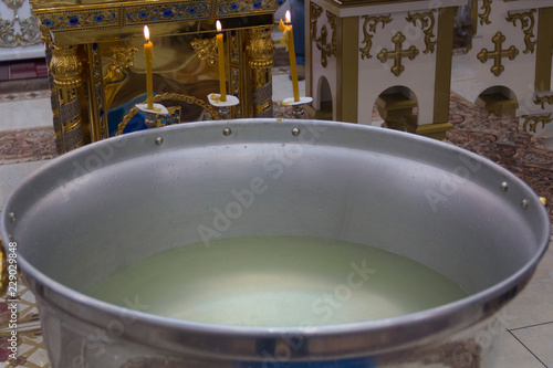 Church font of a metal color for baptism filled with holy water