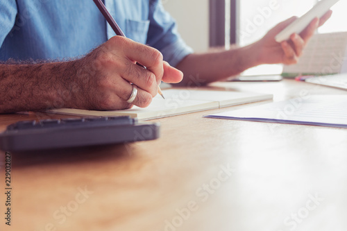 Young man crew works with a new startup program in a modern attic. Pencil handshake laptop analyzes wide horizontal plan in the afternoon.