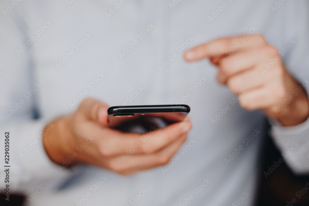 close up of man using smartphone. concept of phone addiction. young business man typing and browsing social media on his phone. close up of man using smartphone. concept of phone addiction. young business man typing and browsing social media on his phone.
