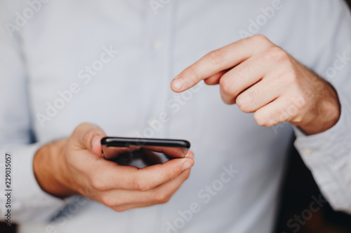 close up of man using smartphone. concept of phone addiction. young business man typing and browsing social media on his phone. 