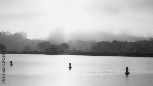 Black and white soft focus view of Russian Hill in San Francisco on a foggy fall morning.  Water and navigation buoy foreground.