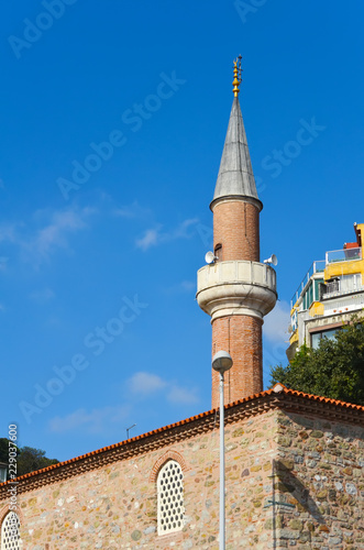 Minaret of a small mosque against the blue sky