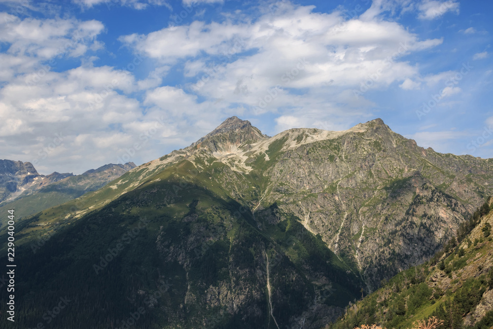 Naklejka premium Closeup view mountains scenes in national park Dombai, Caucasus, Russia, Europe. Summer landscape, sunshine weather, dramatic blue sky and sunny day