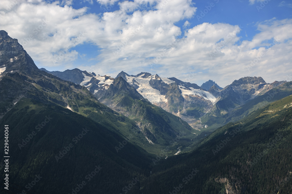 Naklejka premium Closeup view mountains scenes in national park Dombai, Caucasus, Russia, Europe. Summer landscape, sunshine weather, dramatic blue sky and sunny day