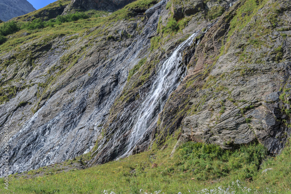 Closeup view waterfall scenes in mountains, national park Dombai, Caucasus, Russia, Europe. Summer landscape, sunshine weather, dramatic blue sky and sunny day