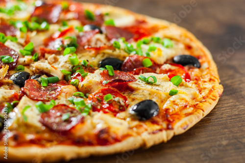 Pizza with Chicken meat  Mozzarella cheese  pepperoni  tomato  olive  salami. Italian pizza on wooden background