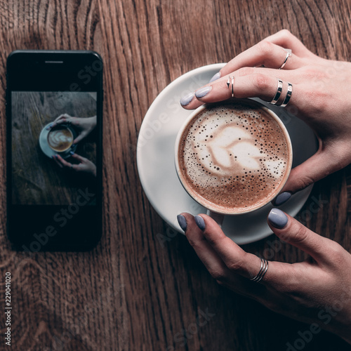 girl holding cofee on wood table with telephone.