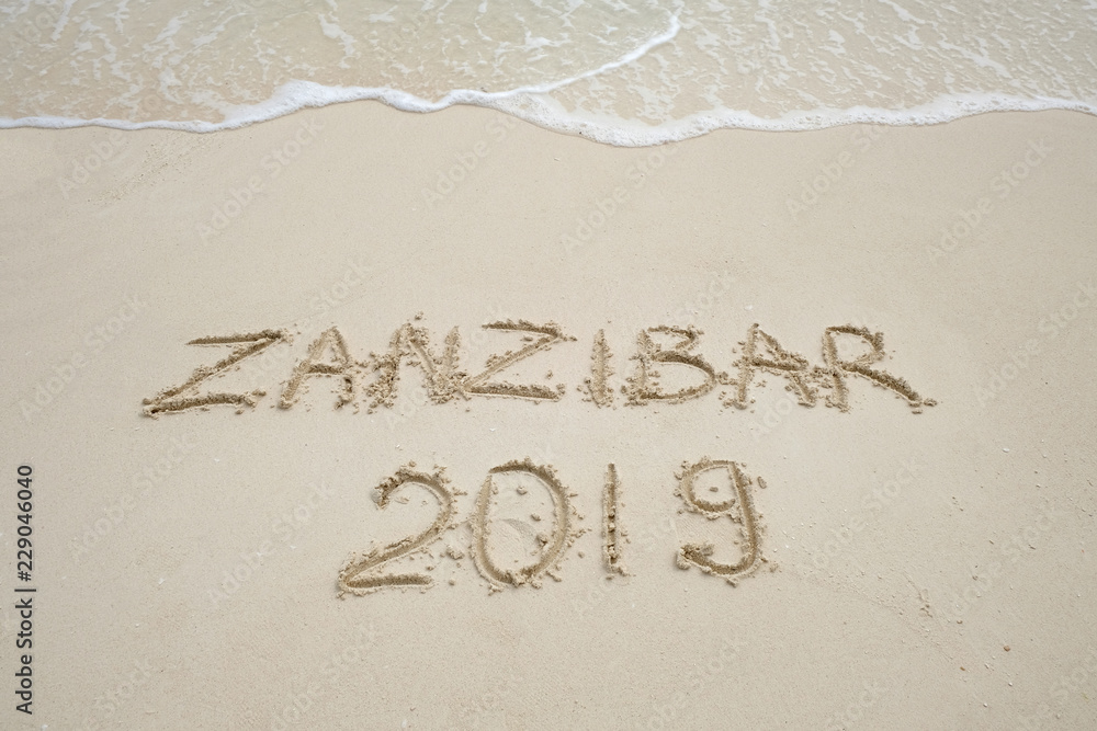 Fototapeta premium Zanzibar napis na jasnym piasku i falach oceanicznych